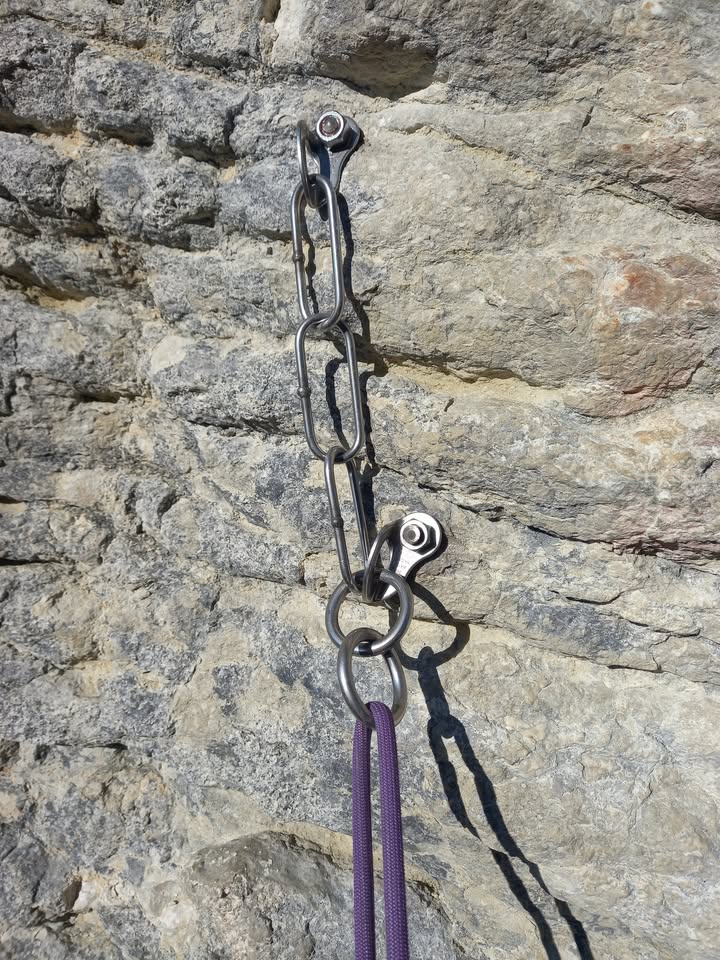 A new stainless steel anchor on the limestone with a purple rope clipped in