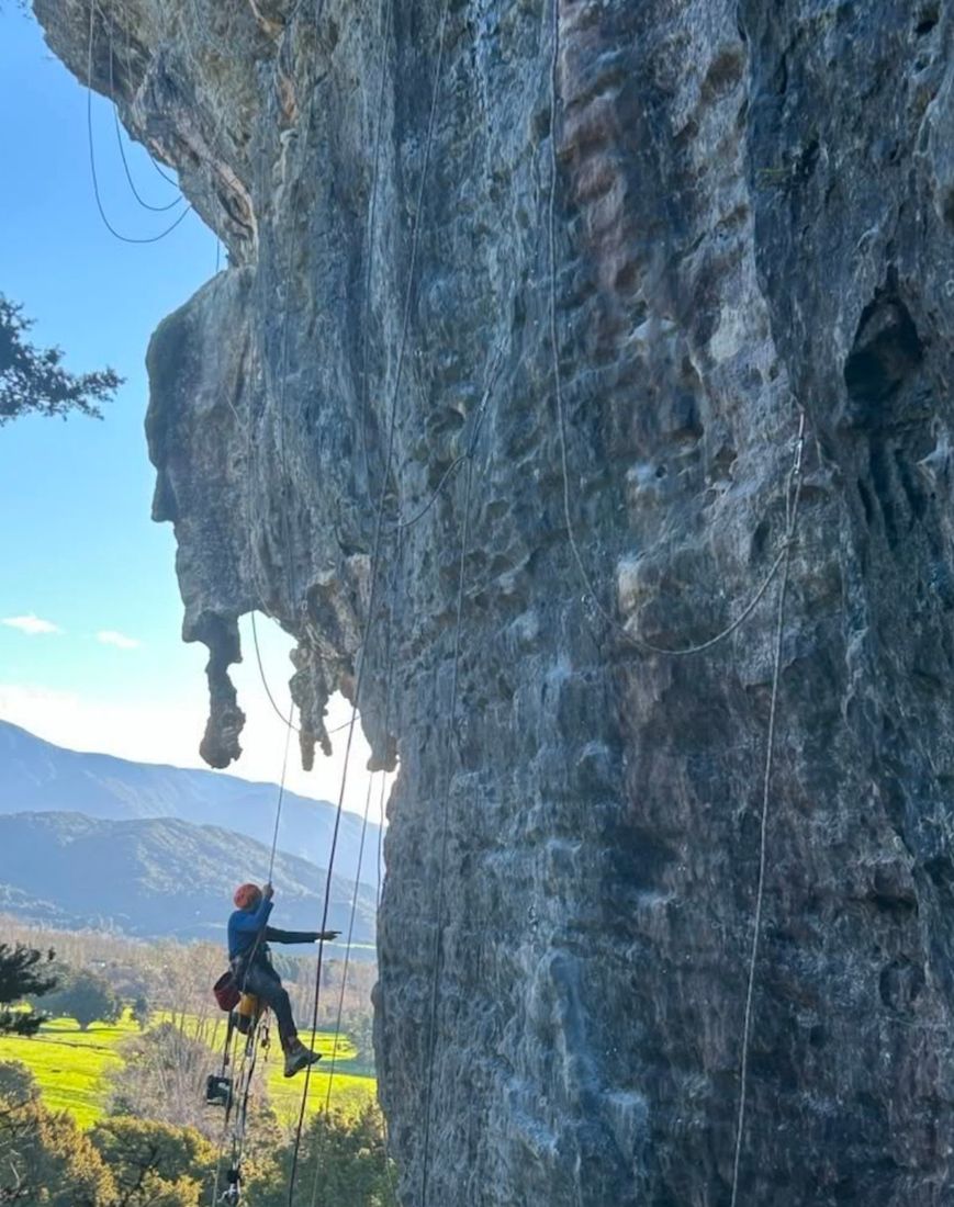 Ropes hanging down Fish Wall, with green farmland and hills behind