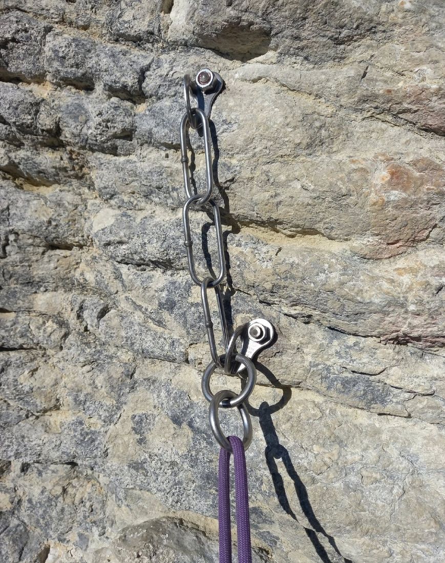 A new stainless steel anchor on the limestone with a purple rope clipped in