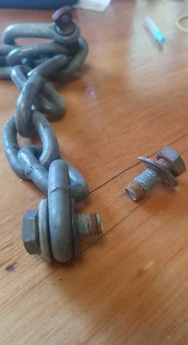 Galvanised chain and two short bolts with rusty threads on a table